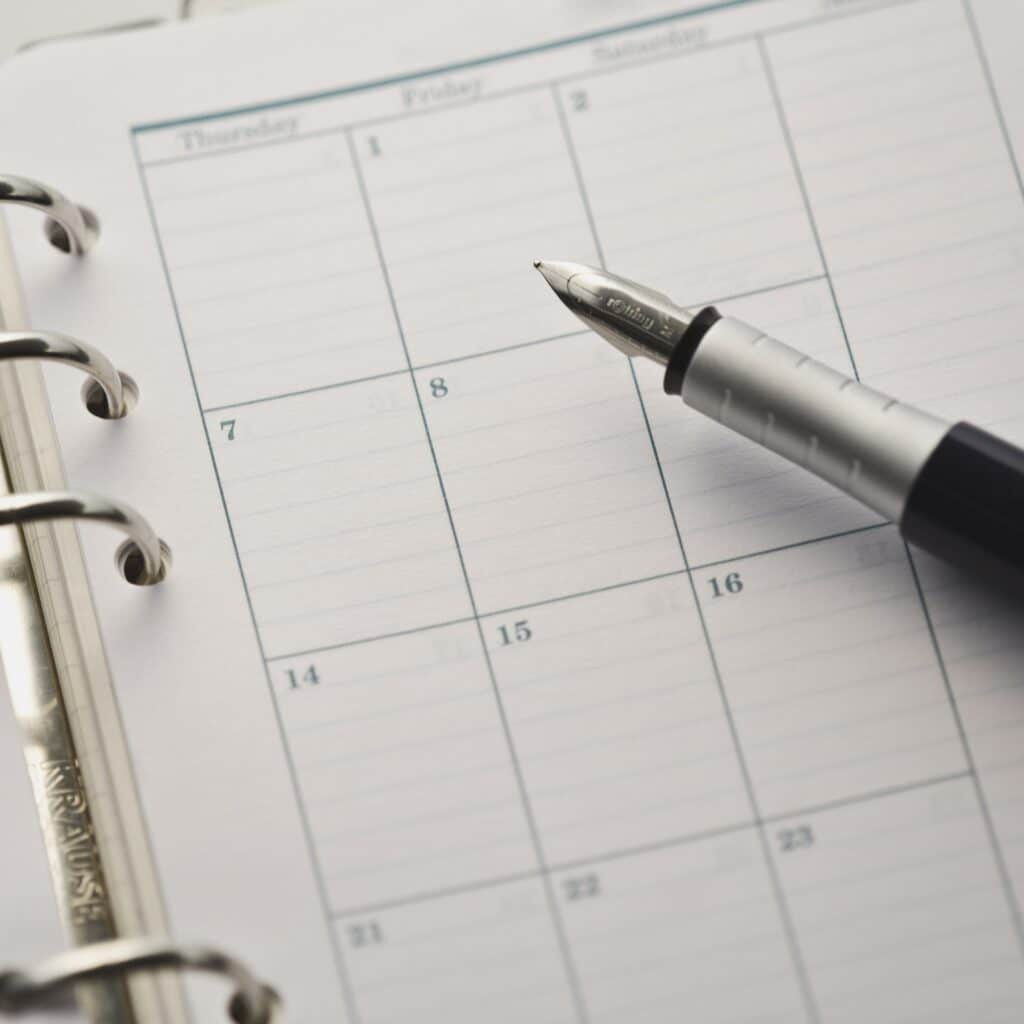 A close-up of a fountain pen resting on an open planner with blank weekly calendar pages, perfect for scheduling pool cleaning or planning your next Inman Pool Service appointment in a convenient spiral-bound format.